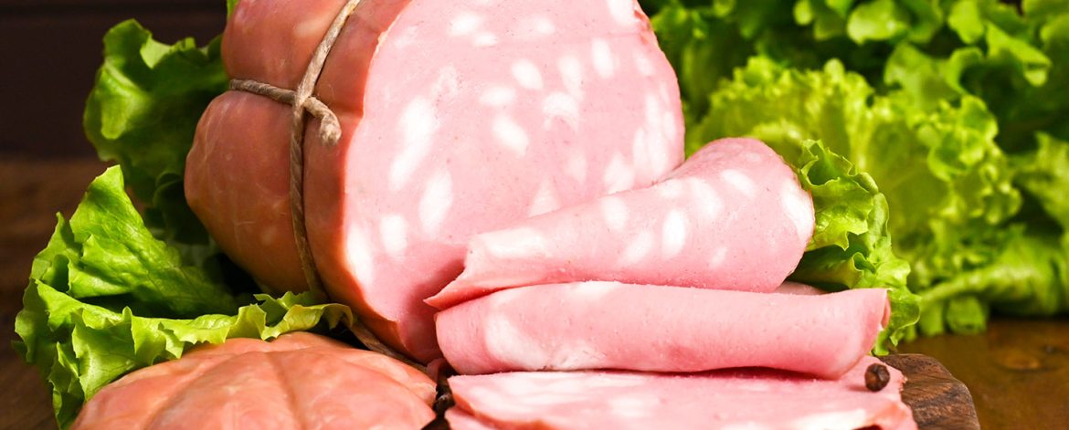 big Italian Whole block of mortadella on a wooden plate. Traditional big sausage and black pepper pistachios Region Emilia Romagna and the city of Bologna. Top view. Copy space big Italian Whole block of mortadella on a wooden plate. Traditional big sausage and black pepper pistachios Region Emilia Romagna and the city of Bologna. Top view. Copy space